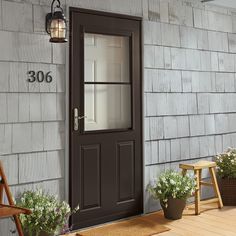 the front door of a house with flowers and potted plants on the porch next to it