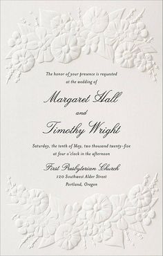 a wedding card with white flowers and leaves on the front, in an ornate frame