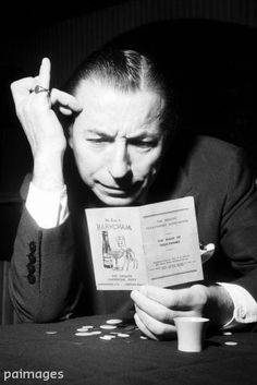 a man sitting at a table holding an open book in front of his face while reading it