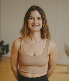 a woman standing with her hands on her hips and looking at the camera, smiling