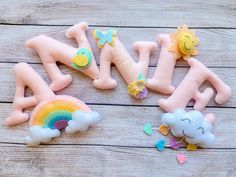 the letters made out of felt are sitting on a wooden surface with rainbows and clouds