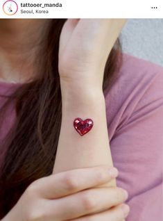 a woman with a heart tattoo on her wrist