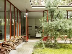 the interior of a modern house with wood stacked on the ground and glass doors open