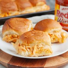 two chicken sliders on a white plate next to a jar of red wing mustard