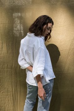 a woman standing in front of a wall with her hands on her hips and looking down