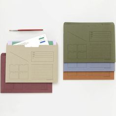 three different colored papers on top of each other next to a pencil and paper pad