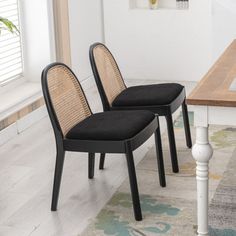 two black chairs sitting next to each other on top of a wooden dining room table