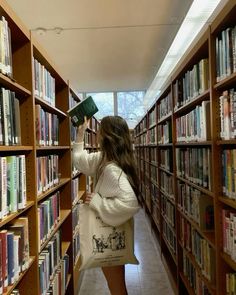 a woman is looking at books in a library with her hand on the book shelf