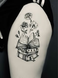 a woman's thigh with an open book and flowers on it