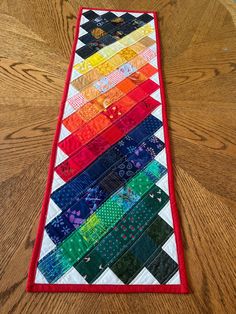 a multicolored table runner made from strips of fabric on top of a wooden floor