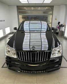 a black car parked in a garage with its hood up and stripes on the front