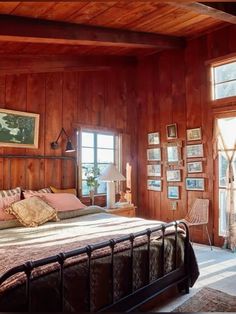 a bedroom with wood paneling and lots of pictures on the wall above the bed