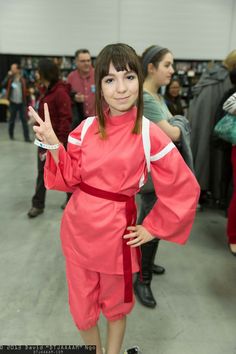 a woman in a red dress posing for the camera with her hand up and two other people standing behind her