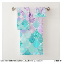 two towels hanging on a towel rack in front of a white wall with blue, purple and green mermaid scales