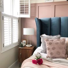 a blue headboard with two roses on it in front of a window and shutters