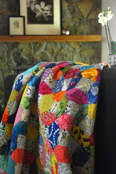 a colorful quilt sitting on top of a couch next to a vase filled with flowers