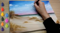 someone is drawing on a paper with watercolors