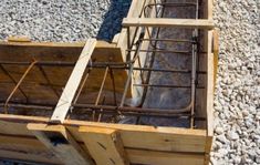 a wooden box filled with lots of metal wire and wood boxes on top of gravel