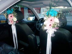 two flower bouquets sitting in the back seat of a car with white ribbons on them