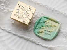 two wax stamps sitting on top of a white lace