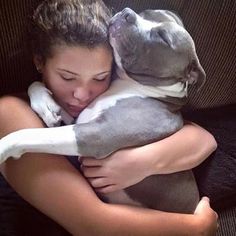 a woman is hugging her dog on the couch