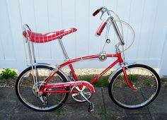 a red bicycle parked next to a white wall