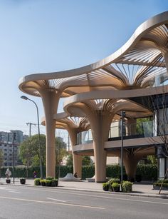 an architecturally designed building on the corner of a street with trees and bushes in front of it