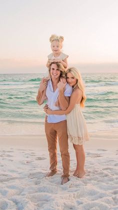 two women and a child are standing on the beach with their arms around each other