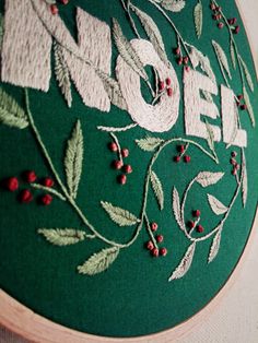 a close up of a embroidery on a piece of cloth with the word noel written in large letters