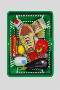 a green shopping basket filled with food and condiments