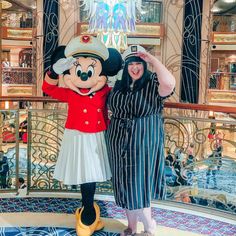 two women standing next to each other in front of a mickey mouse statue on a cruise ship