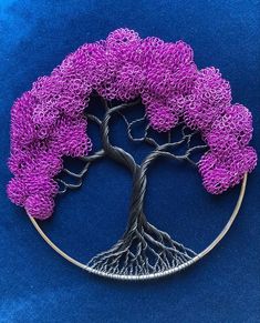 a wire tree with purple flowers in the shape of a circle on a blue background