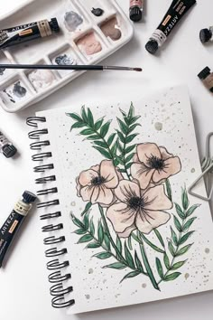 an open notebook with watercolors and flowers on it