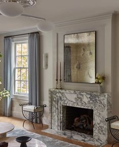 a living room filled with furniture and a fire place in front of a large window