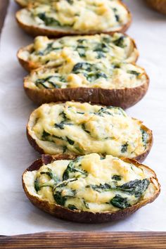 baked potatoes with spinach and cheese are lined up on a baking sheet