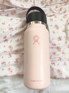 a pink hydro flask water bottle laying on a bed