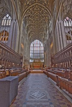 the inside of a large cathedral with pews and stained glass windows on both sides