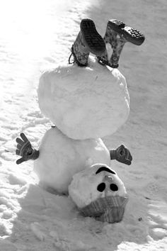 a snowman with skis on his head and feet sticking out of the snow