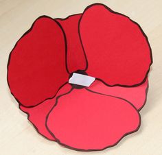 three pieces of red paper sitting on top of a wooden table