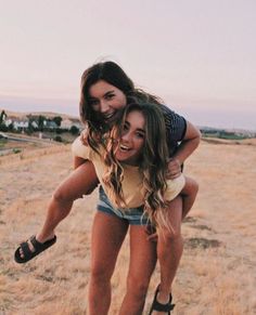 two young women are playing in the grass with each other while one woman is on her back