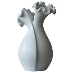 a white vase with two flowers in it on a white background, that appears to be made out of porcelain