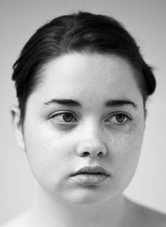 a black and white photo of a woman with freckles on her face looking at the camera