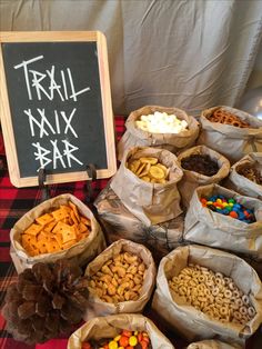 a table topped with bags filled with different types of snacks next to a chalk board