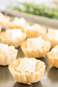 small cupcakes with white frosting sitting on a baking sheet, ready to go into the oven