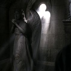 an angel statue in a dark room with light coming from it's side window