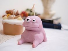 a pink toy sitting on top of a bed next to a cake