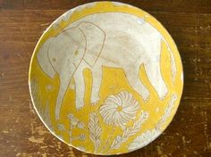 an elephant painted on a yellow and white plate