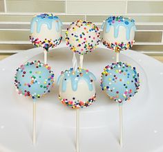 cake pops with sprinkles and blue icing on a white plate