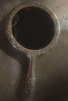 an ornate silver mirror is hanging on a metal surface with a reflection in the mirror