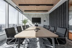 an empty conference room with black chairs and a large wooden table in front of the window